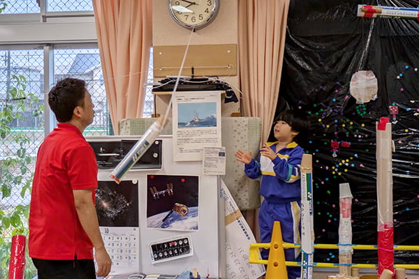 部屋の天井から吊るした自作ロケットを飛ばそうとする子ども