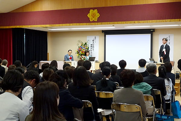 ステージ上の講師３名の鼎談を大勢の参加者が聞いている様子