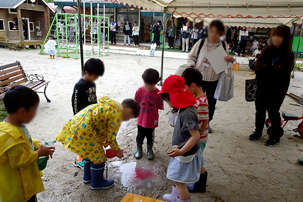 園庭にできた水たまりで色の混色を楽しむ子どもたち
