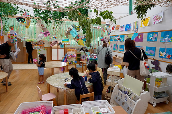 子どもたちが作ったアート作品が飾られている部屋の中で絵具を調合して別の色を作っている5歳児の様子