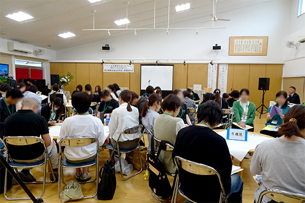 参加者が複数のグループに分かれてテーブルを囲みながら話し合っている様子