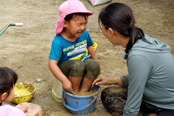 泥の感触を全身で感じながら、保育者と心を通わせる3歳児