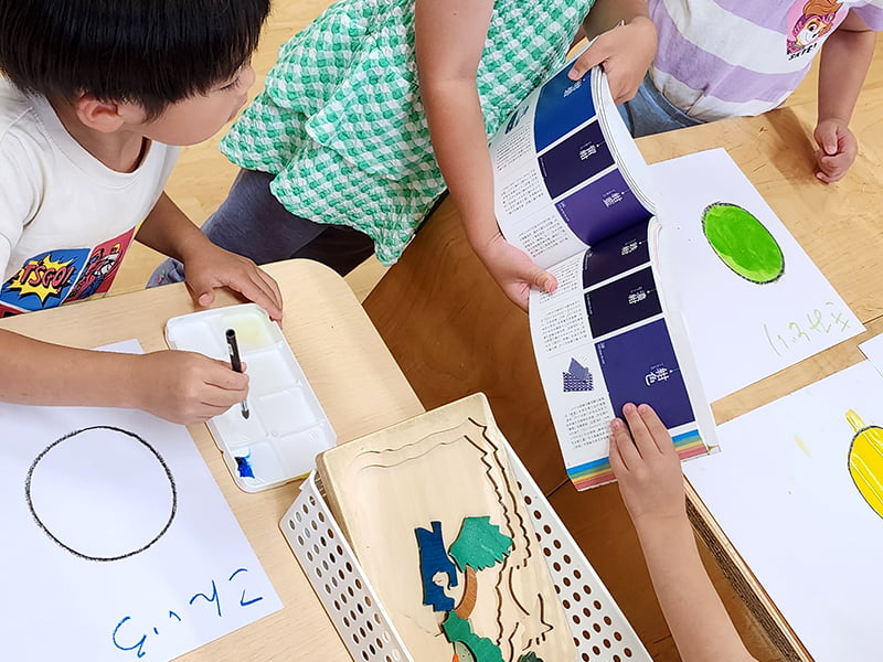 画用紙に丸を描き、色辞典を見ながら同じ色を塗っていく子ども