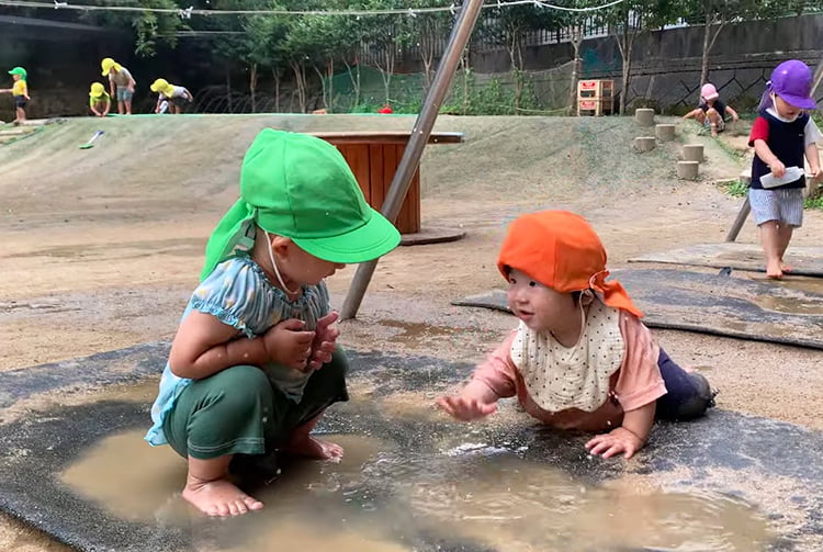 城崎こども園の実践の様子(乳児と幼児が水たまりで遊んでいる様子)